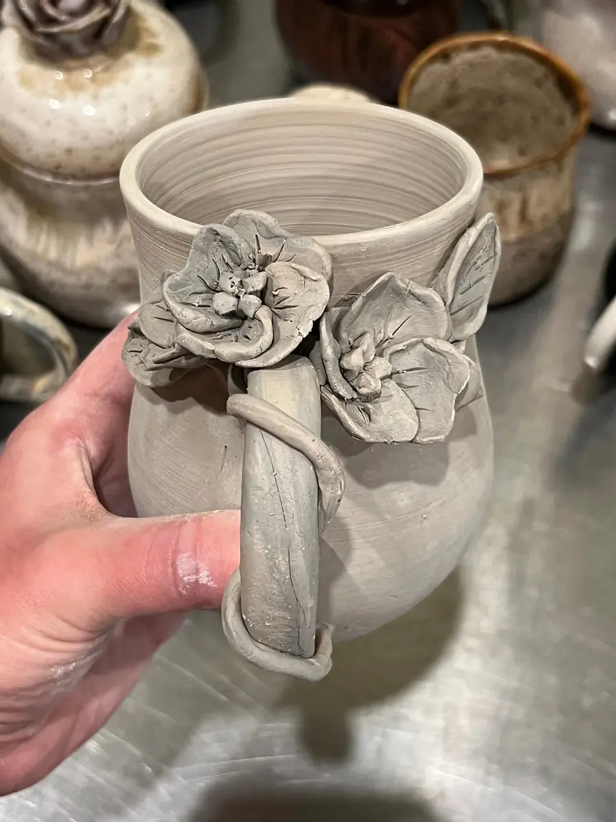 A floral, handcrafted pottery mug.