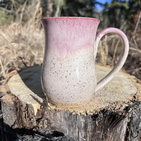 Speckled clay mug with warm white glaze and a pink frosted rim. 