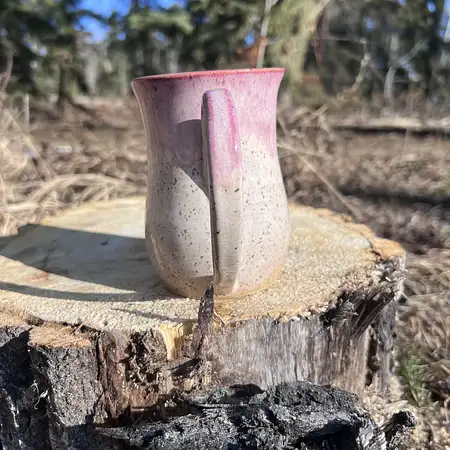 Speckled clay mug with warm white glaze and a pink frosted rim. 