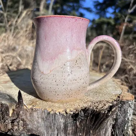 Speckled clay mug with warm white glaze and a pink frosted rim. 