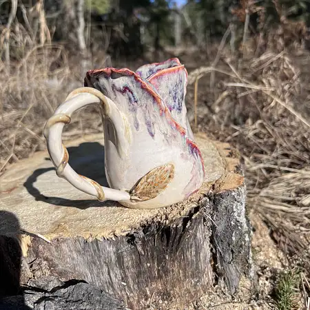 Wheel thrown cup with sculpted clay creating a purple hue rosebud cup. 