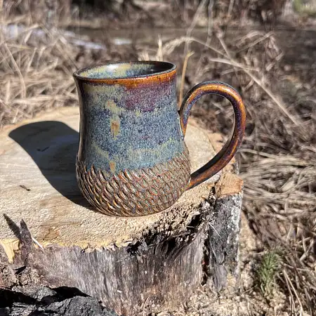 Hand carved wide bottom mug dipped in an earthy blue/brown glaze.