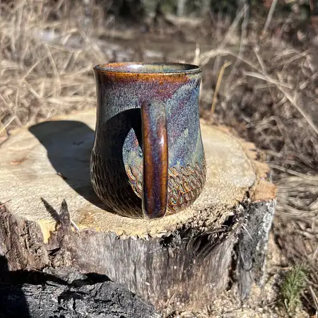 Hand carved wide bottom mug dipped in an earthy blue/brown glaze.