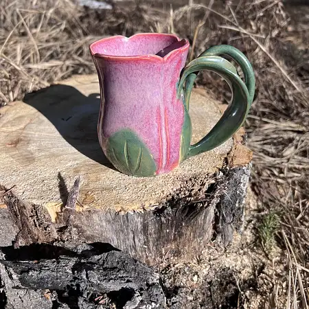 Hand thrown bright pink tulip cup featuring a stem and leaf handle.