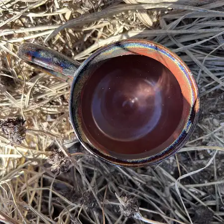 Dark clay thrown and carved in a tree bark pattern leaving the raw clay exposed. Interior and rim is glazed in a rusty dark glaze.