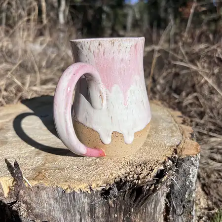 Hand thrown cup featuring speckled clay with a white and pink drippy glaze.
