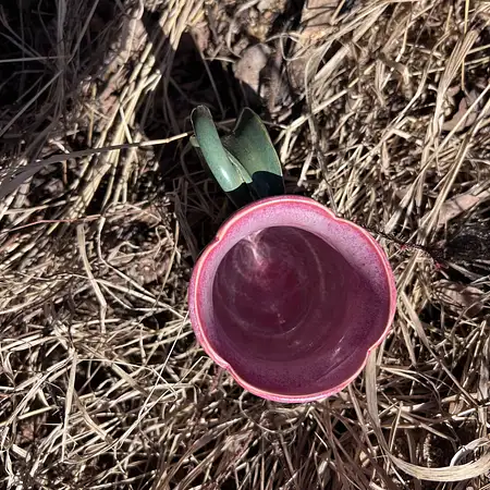 Hand thrown bright pink tulip cup featuring a stem and leaf handle.