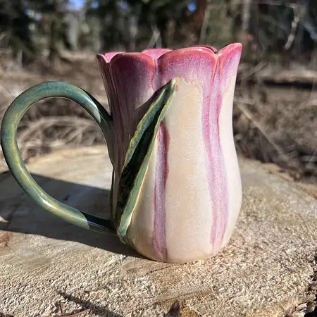Hand thrown, carved and sculpted tulip cup featuring a scallop rim, stem and leaf and pink and white glaze. 