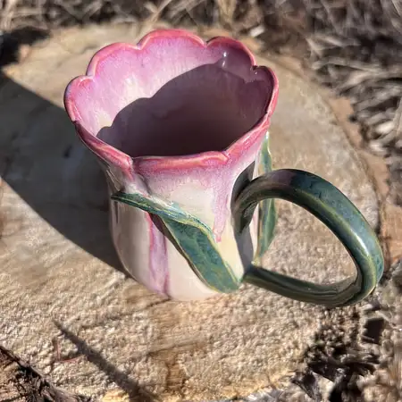 Hand thrown, carved and sculpted tulip cup featuring a scallop rim, stem and leaf and pink and white glaze. 