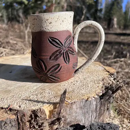 Hand carved floral cup in raw brown clay with a woodsy glaze. Medium sized coffee mug. 